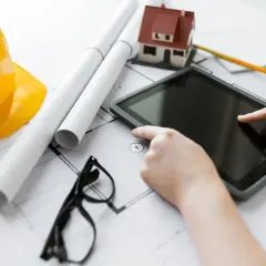 Nowoczesne technologie budowy domu: tablet, plany, model domu, kask i okulary.