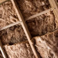Drewniana konstrukcja dachu z wełną mineralną, która stanowi izolację. Instalacja elektryczna w wełnie jest widoczna między belkami.
